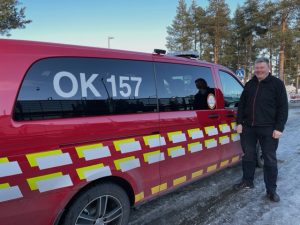 Punainen Oulun VPK:n miehistöauto ja mies kuvan oikeassa reunassa mustassa pusakassa. Autossa tunnus OK 157.