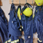 Saarenkylän Vapaaehtoinen Palokunta ry:n nuoriso-osaston siniset harjoitusasut keltaisine kypärineen naulakossa.